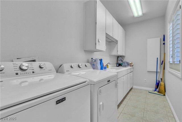 clothes washing area with cabinets, light tile patterned floors, washer and clothes dryer, and sink