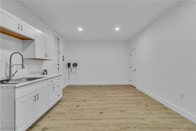 kitchen with white cabinets, light wood-type flooring, and sink