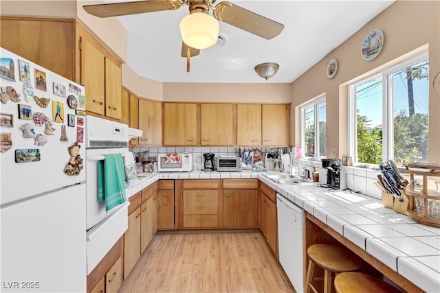 kitchen with sink, tile countertops, white appliances, tasteful backsplash, and light hardwood / wood-style flooring