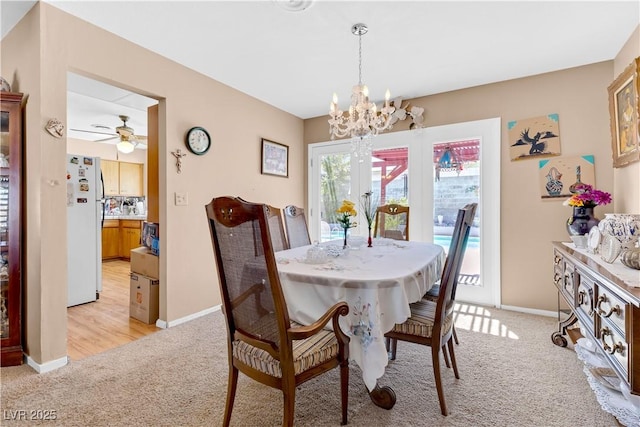 dining area featuring ceiling fan with notable chandelier and light colored carpet