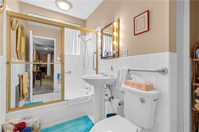 bathroom with toilet, tile walls, and enclosed tub / shower combo