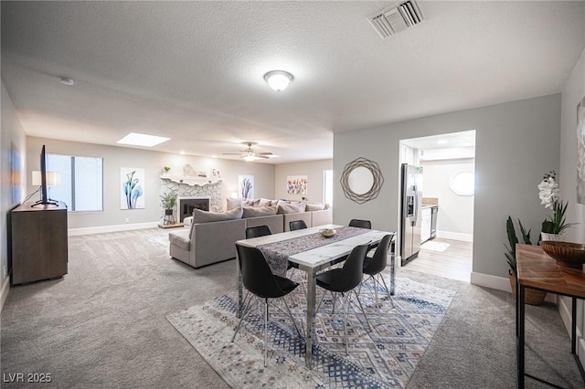 carpeted dining area with ceiling fan, a wealth of natural light, and a textured ceiling