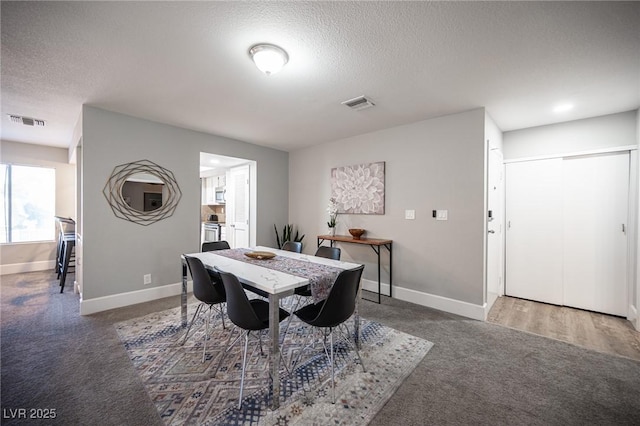 dining area featuring a textured ceiling and dark colored carpet