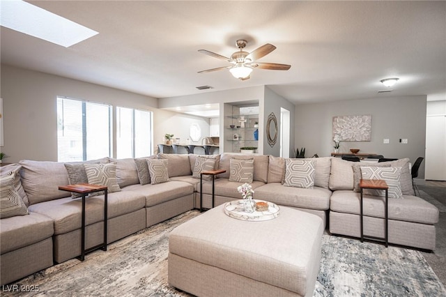 living room with ceiling fan and a skylight