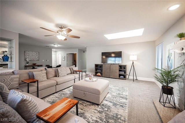 living room with ceiling fan, a skylight, and carpet