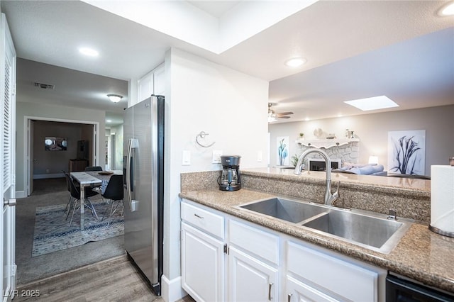 kitchen featuring sink, stainless steel fridge, light hardwood / wood-style flooring, and white cabinets