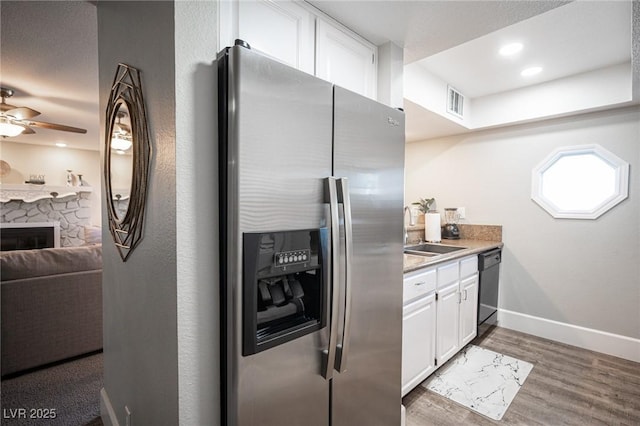 kitchen with sink, white cabinets, black dishwasher, hardwood / wood-style floors, and stainless steel refrigerator with ice dispenser