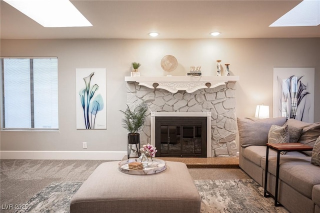 living room with a fireplace, carpet floors, and a skylight