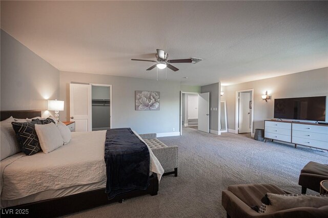 bedroom featuring ceiling fan, a walk in closet, a closet, and carpet floors