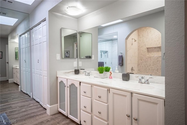 bathroom with a skylight, hardwood / wood-style floors, vanity, and a shower