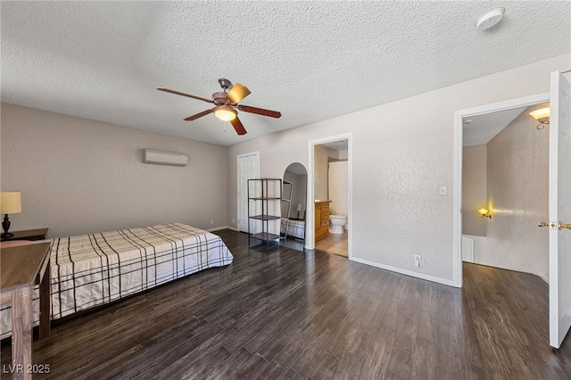 bedroom with dark hardwood / wood-style flooring, a textured ceiling, ceiling fan, and a wall mounted AC