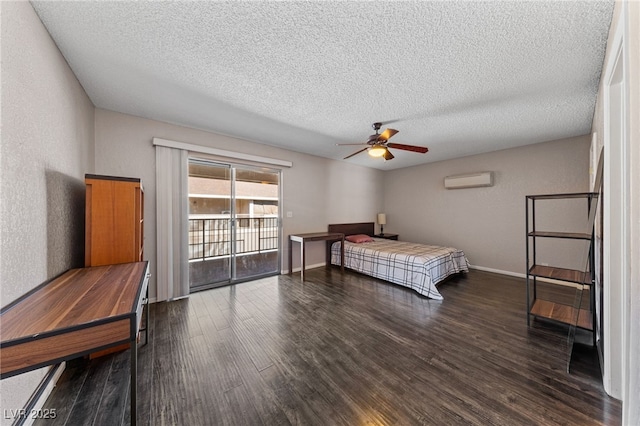 bedroom with access to outside, dark wood-type flooring, a textured ceiling, a wall unit AC, and ceiling fan