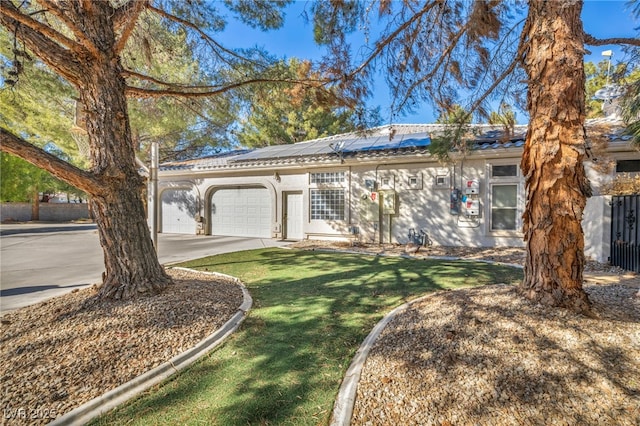 ranch-style house featuring solar panels, a front yard, and a garage