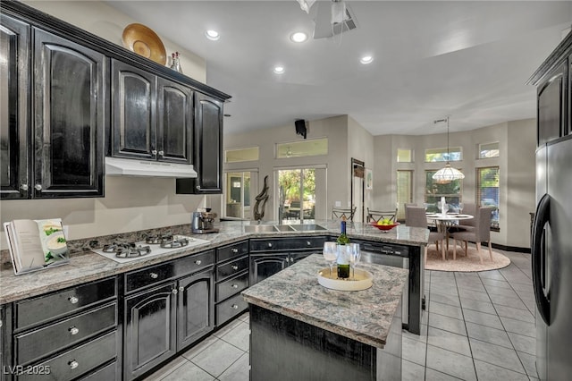 kitchen with light stone countertops, pendant lighting, a center island, appliances with stainless steel finishes, and light tile patterned flooring