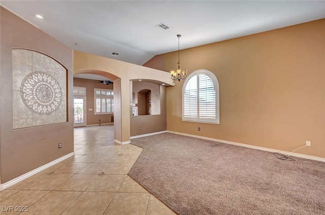 tiled empty room with lofted ceiling and ceiling fan with notable chandelier