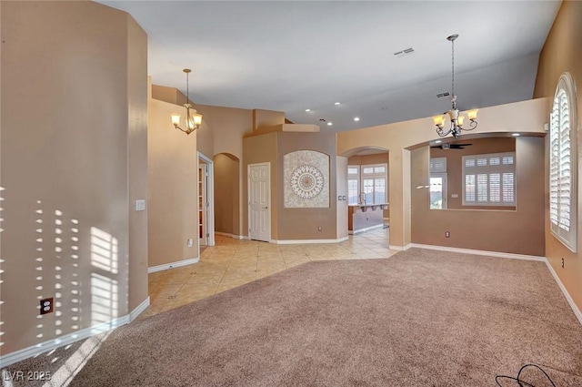 unfurnished living room with ceiling fan with notable chandelier and light colored carpet