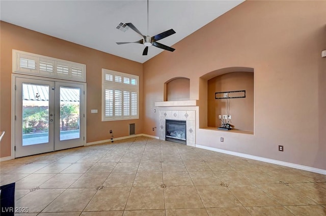 unfurnished living room featuring a tile fireplace, french doors, ceiling fan, light tile patterned floors, and high vaulted ceiling