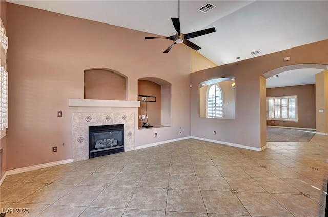 unfurnished living room featuring ceiling fan, a tile fireplace, vaulted ceiling, and light tile patterned floors