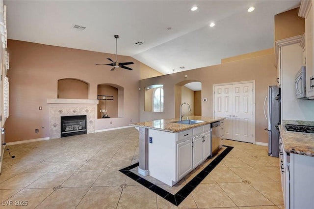 kitchen with light stone counters, an island with sink, white cabinets, appliances with stainless steel finishes, and sink