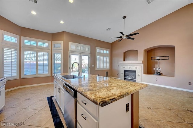 kitchen with sink, white cabinets, dishwasher, light tile patterned floors, and a kitchen island with sink