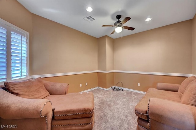 living area with a wealth of natural light, ceiling fan, and carpet flooring