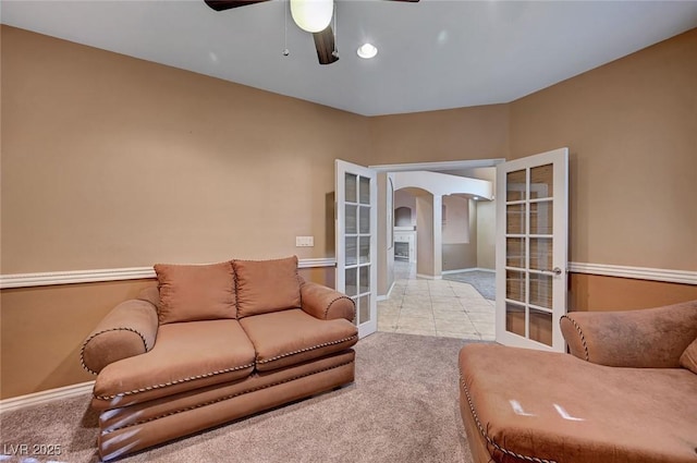 carpeted living room with ceiling fan and french doors