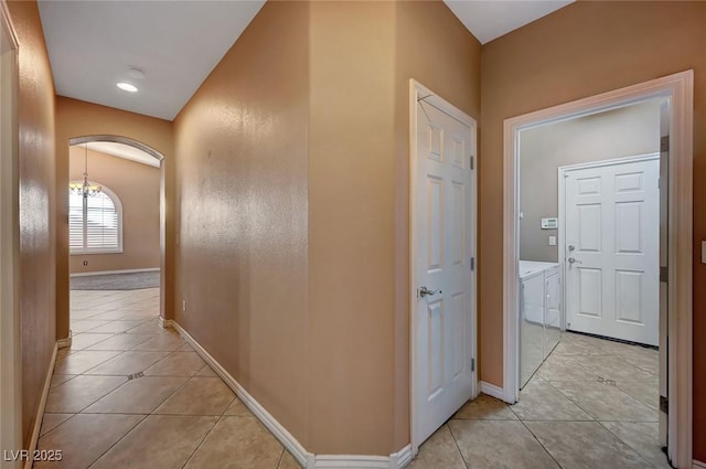 corridor featuring an inviting chandelier and light tile patterned flooring