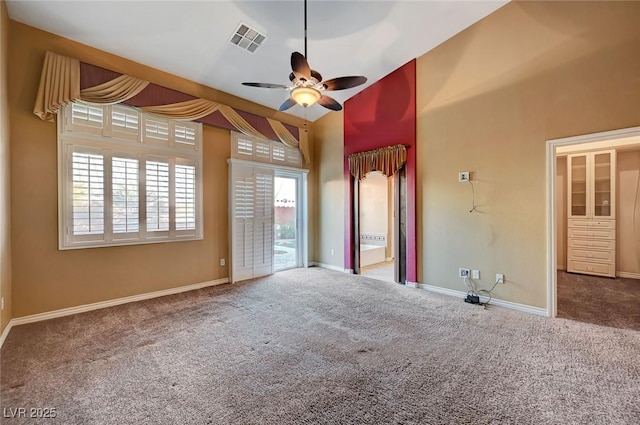 carpeted spare room featuring ceiling fan and a high ceiling