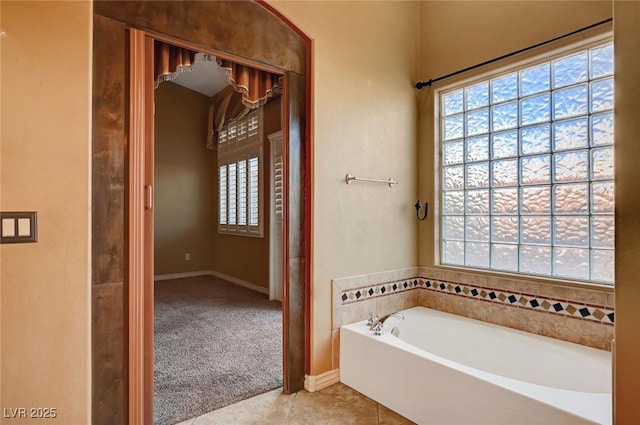 bathroom with a washtub, tile patterned flooring, and a healthy amount of sunlight