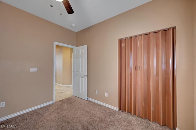 unfurnished bedroom with ceiling fan, light colored carpet, and a closet