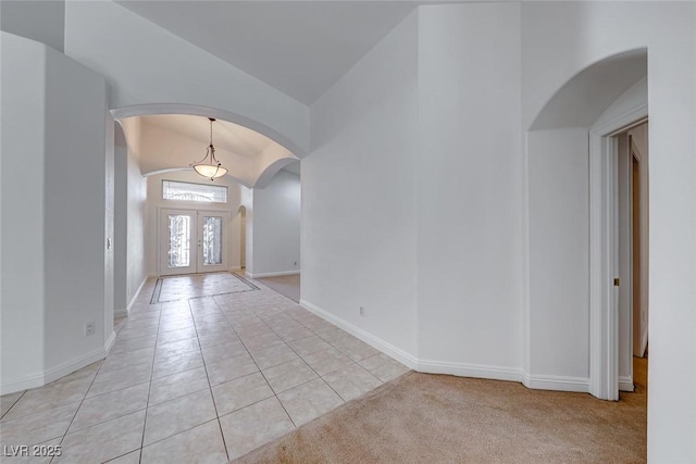 foyer entrance with vaulted ceiling, light tile patterned flooring, and french doors