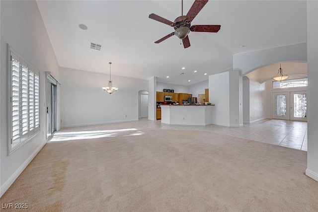 unfurnished living room featuring light colored carpet, french doors, lofted ceiling, and ceiling fan with notable chandelier