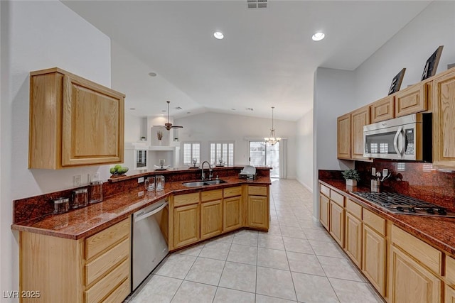 kitchen with kitchen peninsula, vaulted ceiling, hanging light fixtures, appliances with stainless steel finishes, and sink