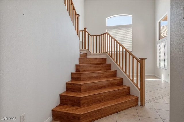 stairs with a high ceiling, tile patterned flooring, and plenty of natural light