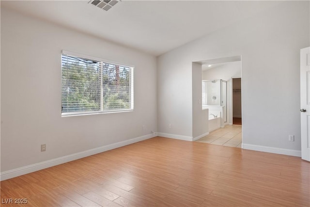 unfurnished room featuring light wood-type flooring and vaulted ceiling