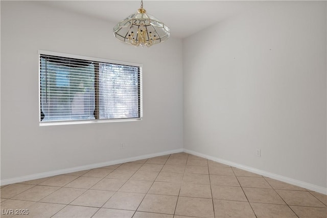 tiled spare room with a notable chandelier