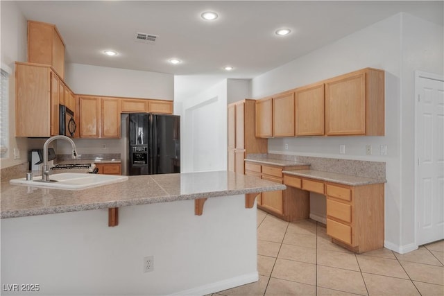 kitchen featuring a breakfast bar, light brown cabinetry, and black appliances