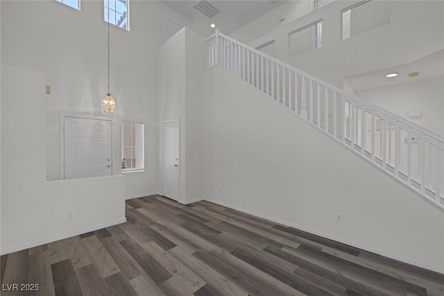 unfurnished living room featuring a towering ceiling and dark hardwood / wood-style floors