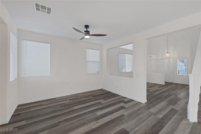 unfurnished room featuring ceiling fan, dark wood-type flooring, and plenty of natural light