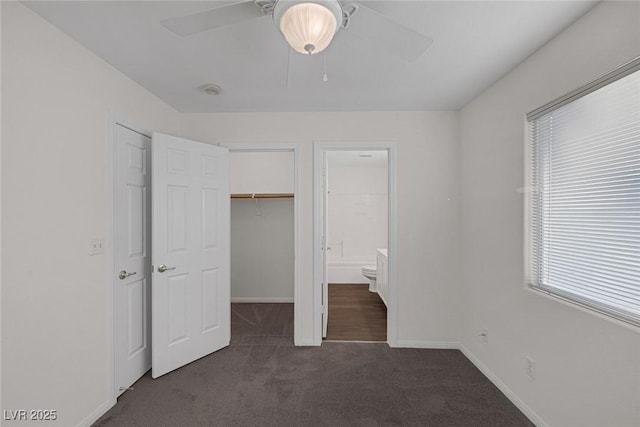 unfurnished bedroom with ensuite bath, ceiling fan, and dark carpet