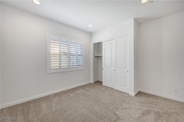 unfurnished bedroom featuring light colored carpet and a closet