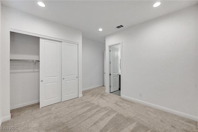 unfurnished bedroom with light carpet and a closet