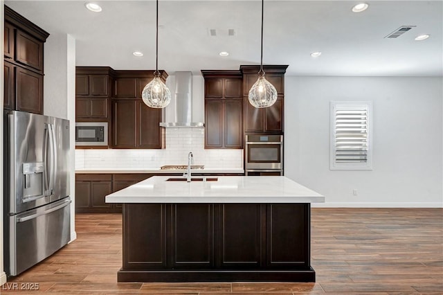 kitchen with decorative light fixtures, built in microwave, stainless steel fridge, and wall chimney range hood