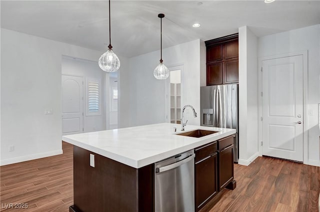 kitchen featuring decorative light fixtures, sink, stainless steel dishwasher, and an island with sink