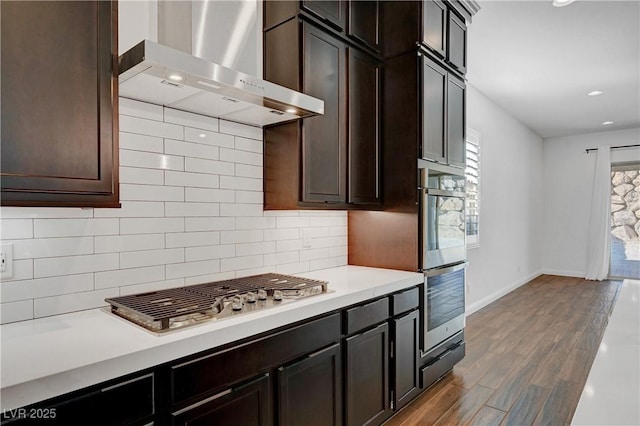 kitchen featuring a wealth of natural light, backsplash, appliances with stainless steel finishes, and wall chimney range hood