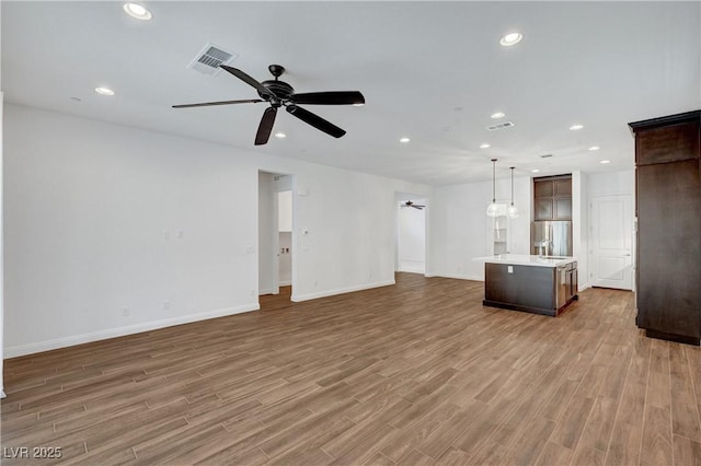 unfurnished living room featuring ceiling fan and hardwood / wood-style floors