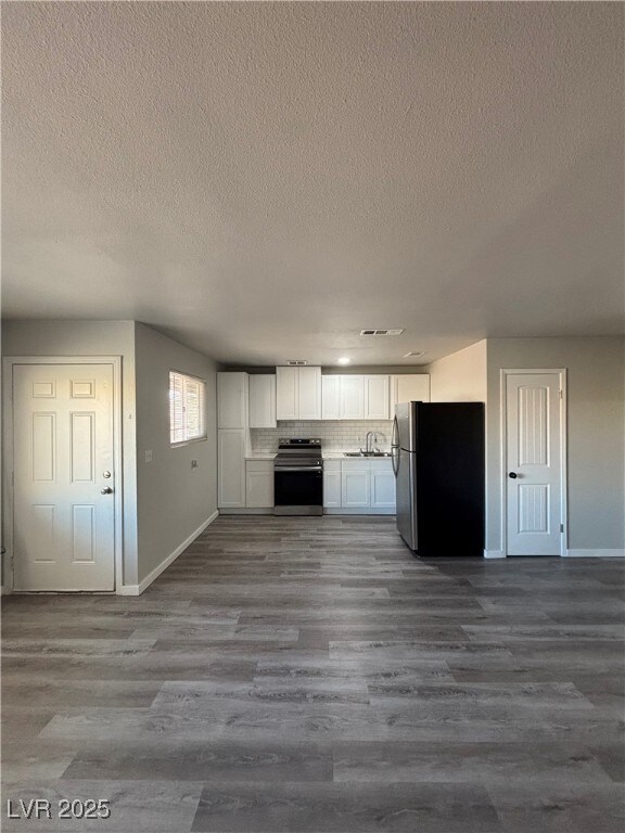 kitchen featuring decorative backsplash, dark hardwood / wood-style flooring, white cabinetry, appliances with stainless steel finishes, and sink