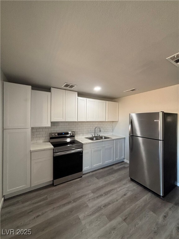 kitchen with sink, white cabinetry, tasteful backsplash, light hardwood / wood-style flooring, and appliances with stainless steel finishes