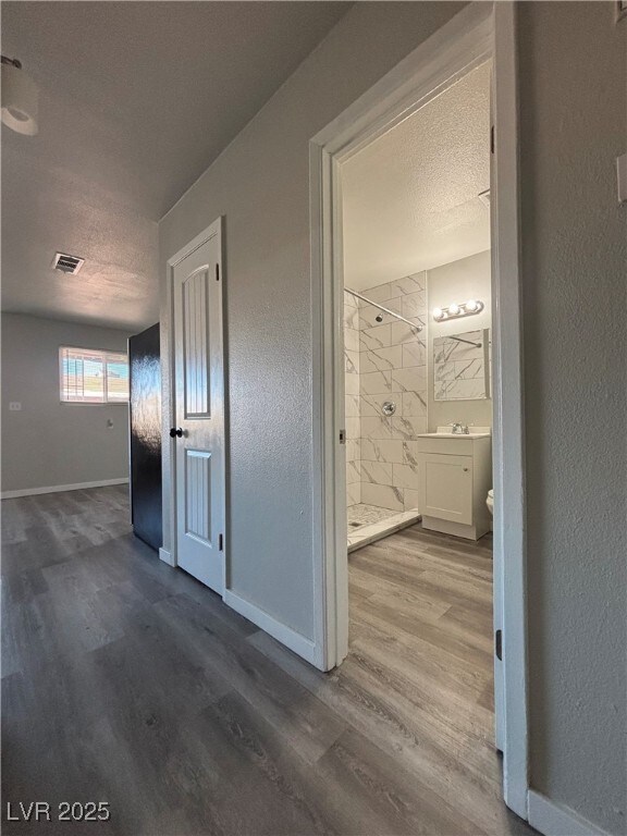 hallway featuring hardwood / wood-style flooring, a textured ceiling, and sink