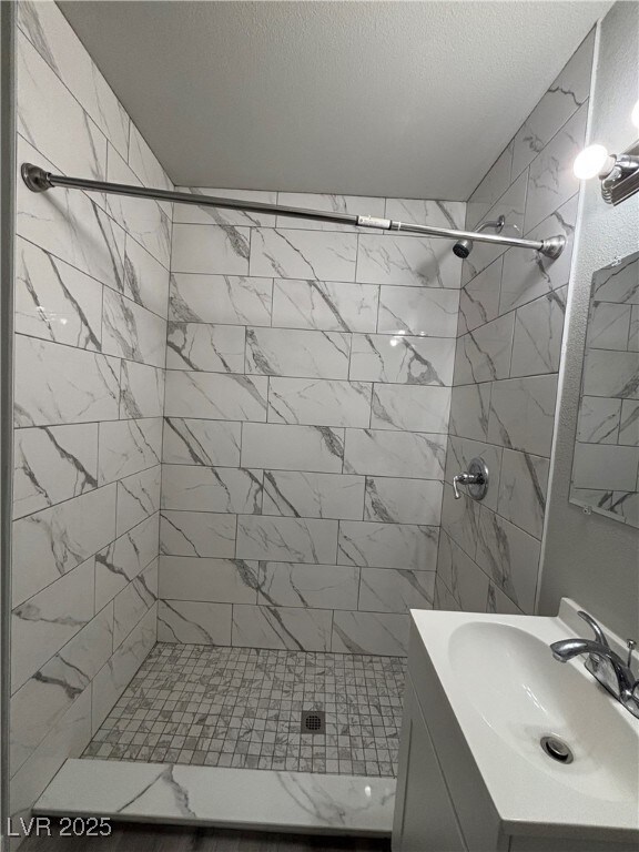 bathroom featuring tiled shower and vanity